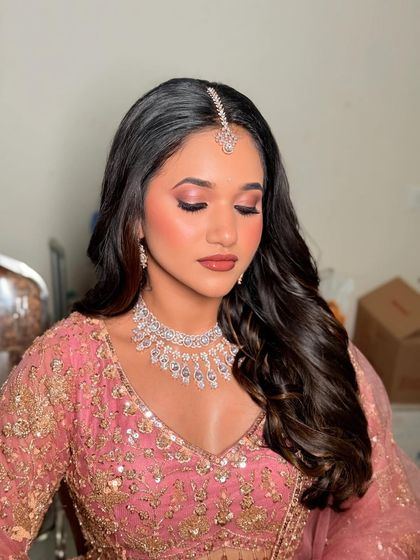 A moment of elegance. The soft pink tones in her makeup and outfit create a romantic and dreamy feel.