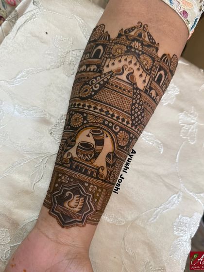 A detailed view of a traditional bridal armband, featuring peacocks, elephants, and ceremonial pots.