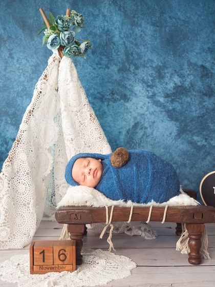A cozy camping theme under a blue sky. The lace tent, wooden props, and deep blue wrap come together for a dreamy and imaginative newborn portrait.