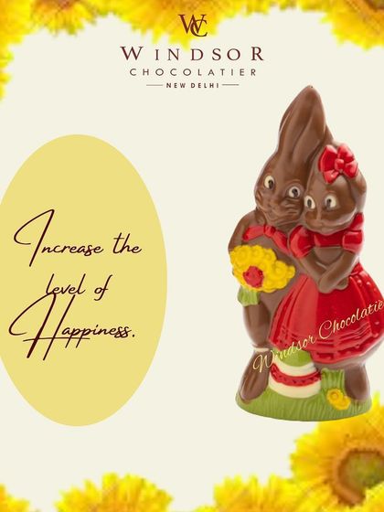 A sweet pair of chocolate bunnies, dressed in red outfits and holding flowers, making a perfect gift for Easter or a loved one.