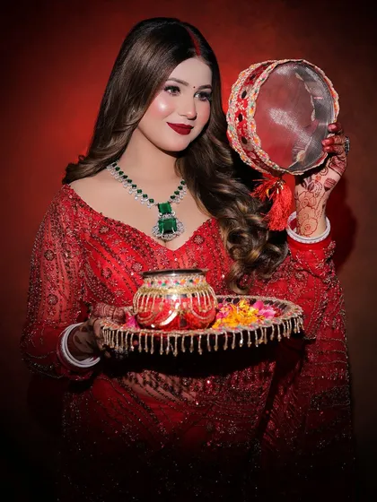 A beautiful portrait of a model ready for Karwa Chauth in a heavy red sequined saree and emerald jewelry.