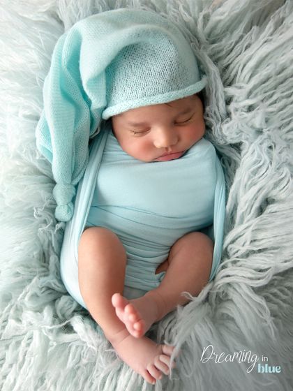 Adding a sleepy hat to the light blue swaddle creates a whimsical and charming portrait. The hat completes the look while keeping the baby cozy.