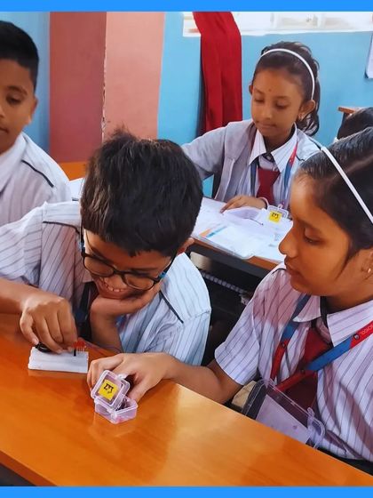 Four students are huddled around a desk, working together to connect components on a breadboard. This image perfectly captures the collaborative and focused nature of our hands-on sessions.