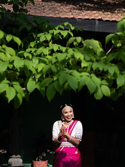 A bride in a pink saree, framed by the lush greenery of our gardens, a vibrant and happy shot.