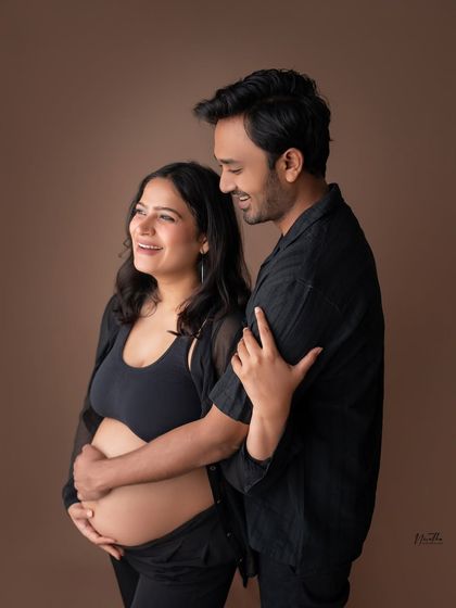 A happy, candid moment from a couple's studio maternity shoot.