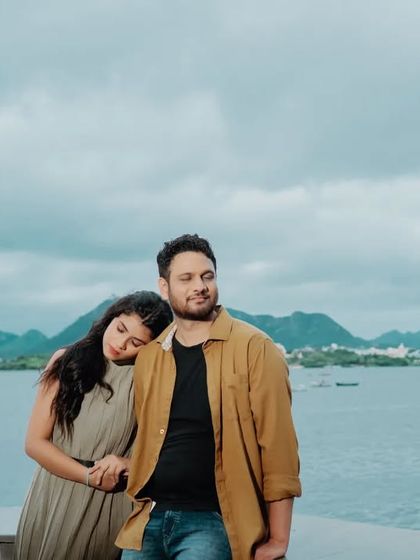 A relaxed and natural moment with the bride-to-be resting her head on her partner's shoulder, set against the expansive view of Lake Pichola in Udaipur.