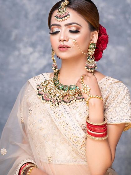 An elegant off-white embroidered lehenga paired with a contrasting green and pink beaded jewellery set. This rental look is perfect for a sophisticated daytime event or reception.