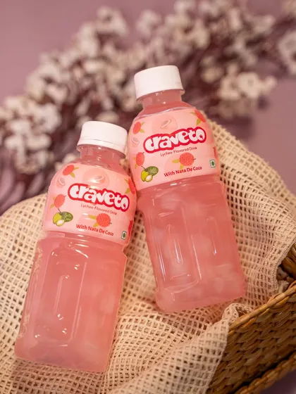 Two bottles of lychee-flavored juice nestled in a woven basket with a soft cloth. This styling creates a gentle, natural, and appealing aesthetic.