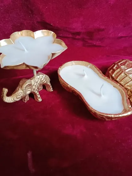 An elephant urli candle holder placed next to a peanut urli candle to show a comparison of two popular designs.