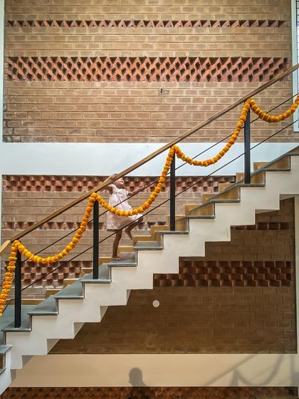A child joyfully running up the stairs against a backdrop of intricate brick jaali work. This candid moment captures the essence of what we strive to create: a home that is a happy, living space.