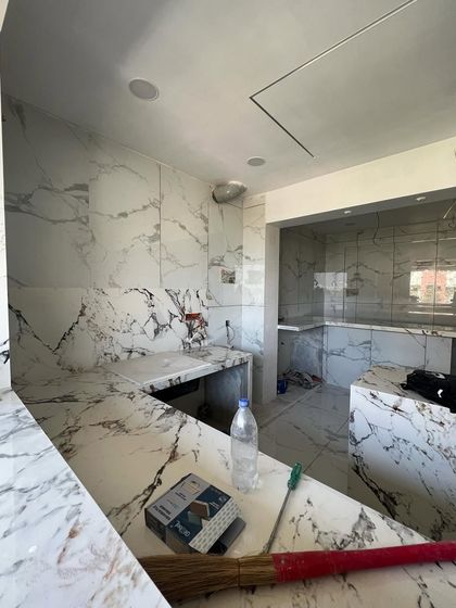 This image captures the kitchen in its early construction phase, with the foundational countertop and tiling work laid out. This stage is crucial for establishing the kitchen's structure and utility points before the final finishes are applied.