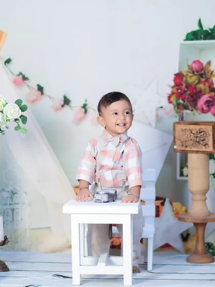 A candid shot of a one-year-old boy standing and looking off to the side, captured in our beautifully decorated studio setup.