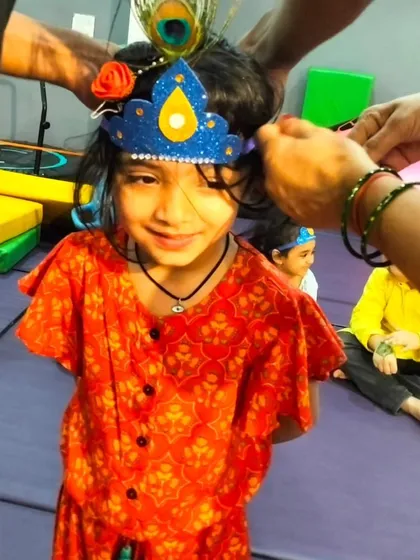 Getting the final touches just right. We help the kids put on their handmade crowns and peacock feathers, making our Janmashtami celebration feel authentic and fun.