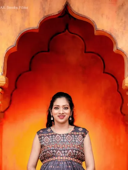A close-up portrait of the expecting mother, showcasing her radiant smile. The architectural backdrop and soft lighting create an elegant and polished look.