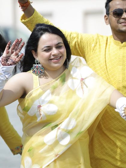 A candid shot of the bride dancing at her Haldi ceremony. She wanted something light and playful, so we chose this beautiful hand-painted organza saree.