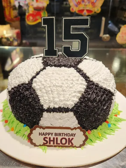 A winning cake for a football fan's 15th birthday. This sculpted soccer ball cake sits on a field of green buttercream grass, making it a great centerpiece for a sports-themed party.