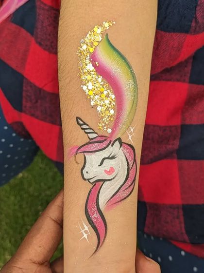 A magical unicorn arm tattoo with a sparkling trail of gold glitter.