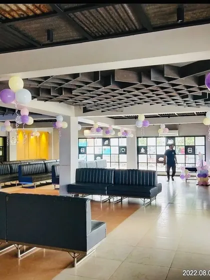 A wide view of the banquet hall decorated with pastel balloon bunches on the ceiling for a baby shower.