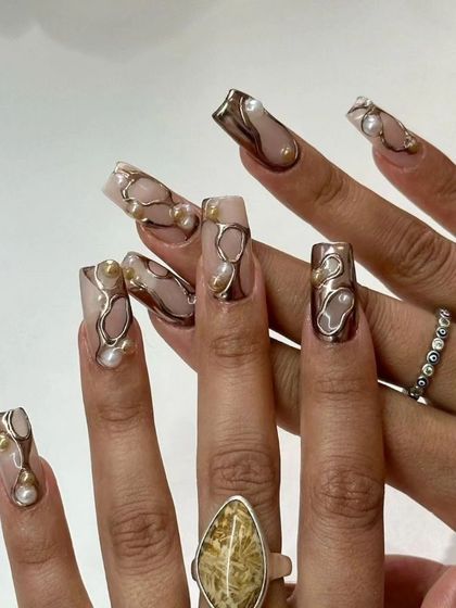 An abstract and artistic set featuring 3D metallic silver and gold shapes over a nude base, accented with pearls.