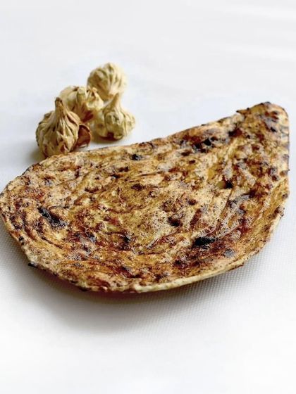 Our black garlic naan, served alongside the smoked garlic bulbs that give it its unique, complex flavour. It’s a beautiful bridge between the simplicity of a butter naan and a different dimension of taste.