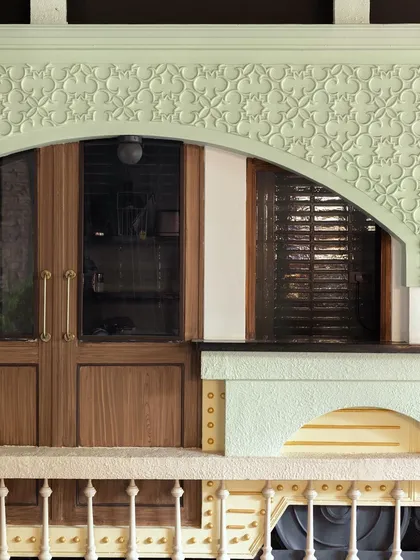 A close-up of the architectural details at Soley Cafe. The pastel green arch with intricate molding and the warm wood of the doors reflect a blend of European classicism and modern craftsmanship.