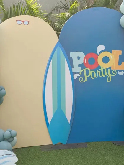 A simple and stylish pool party photo backdrop with a surfboard prop, perfect for capturing summer memories.