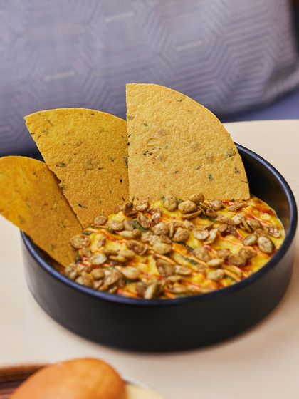 Our Sweet Corn Khichdi is pure comfort in a bowl. Creamy, sweet, and savory, it's topped with spiced, crunchy seeds and served with crispy mathri for dipping.