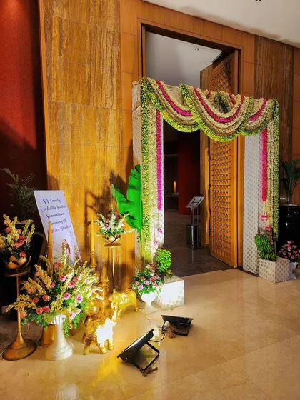 A wide view of the entrance decoration for a baby shower. The setup includes a floral arch, a welcome board, and beautiful lighting.