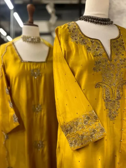 A close-up of a mustard yellow kurta with intricate embroidery on the neckline and sleeves, paired with a statement necklace.