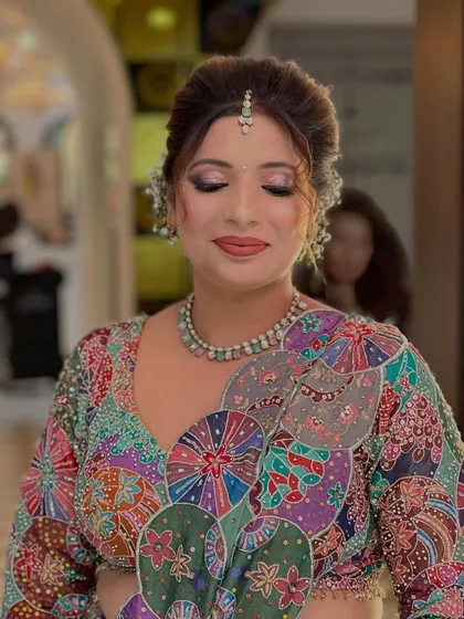 A beautiful party look featuring a colorful, artistic blouse. The makeup is soft and glamorous, with shimmery lilac eyeshadow and a matching lip color.