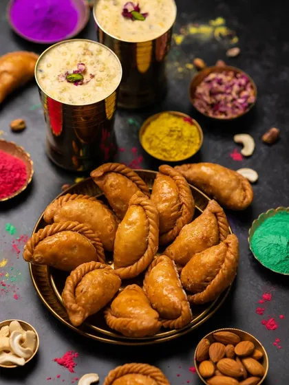A vibrant spread for the Holi festival, featuring Gujjiya and Thandai. The colors of the festival are incorporated into the styling to create a lively and celebratory mood.