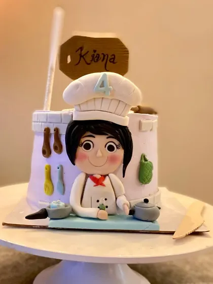A wider shot of the adorable chef-themed cake, ready for its close-up.