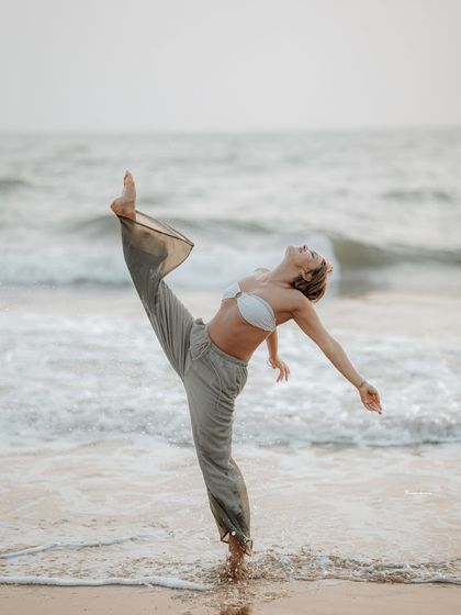 A powerful and graceful pose, perfectly balanced against the moving waves. This image is ideal for fitness, dance, or yoga-themed beach photography.