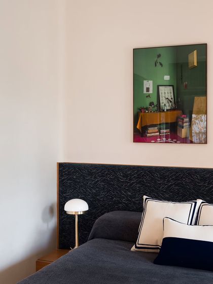 This guest bedroom features a custom bed with a headboard upholstered in a dark, textured fabric. The design is simple and elegant, creating a comfortable and welcoming space for visitors.