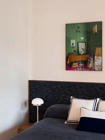 This guest bedroom features a custom bed with a headboard upholstered in a dark, textured fabric. The design is simple and elegant, creating a comfortable and welcoming space for visitors.