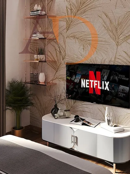 This modern bedroom TV unit features a sleek white console against a wall with a subtle golden palm print wallpaper, creating an elegant media space.