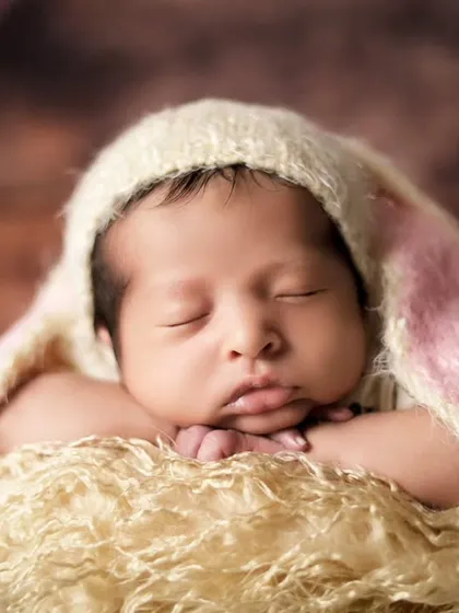 A close-up of the 'chin on hands' pose, one of the most classic and adorable newborn poses. It requires a lot of patience and skill to achieve safely.