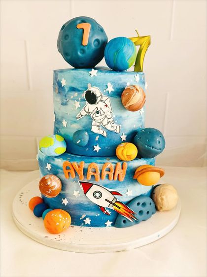 A two-tier galaxy cake with hand-painted watercolor effects and edible planets.