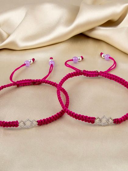 A pair of bright pink woven bracelets with a geometric silver charm.