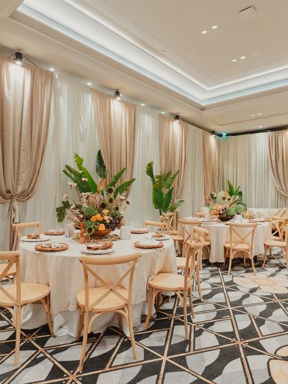 The dining setup for the carnival event, featuring wooden cross-back chairs and lush, low centerpieces that encouraged conversation while maintaining the elegant, natural aesthetic.