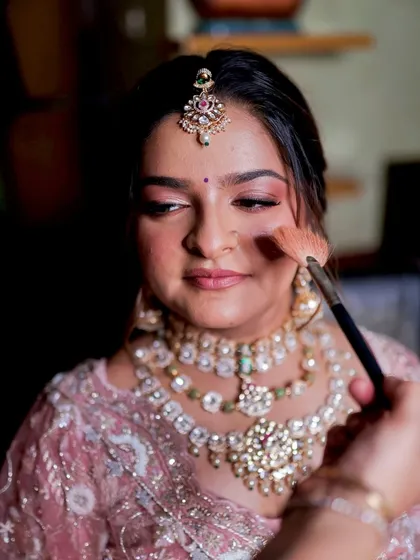 A behind the scenes moment, applying blush to create a healthy, natural-looking flush that enhances the bride's glow.