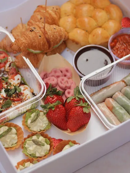 Our 'Friends Specials' Valentine's Day Grazing Box is perfect for sharing. It includes croissants, pull-apart bread, caprese salad, spring rolls, and sweet treats.