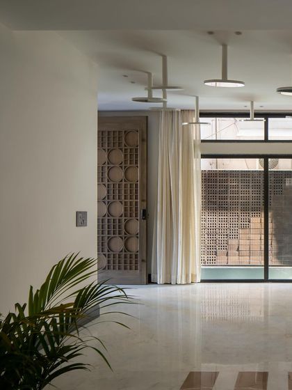 A detail of the entrance foyer, with its custom carved wooden door and a view towards the water body. The space is designed to create a sense of tranquility upon arrival.