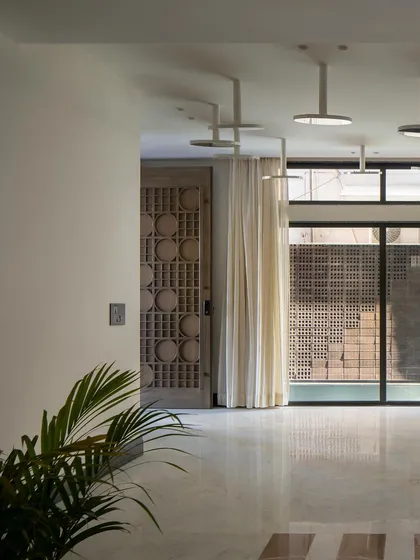 A detail of the entrance foyer, with its custom carved wooden door and a view towards the water body. The space is designed to create a sense of tranquility upon arrival.