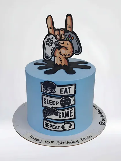 A cool gaming-themed cake for a 15th birthday. The "Eat, Sleep, Game, Repeat" mantra and controller topper perfectly capture the life of a teenage gamer.
