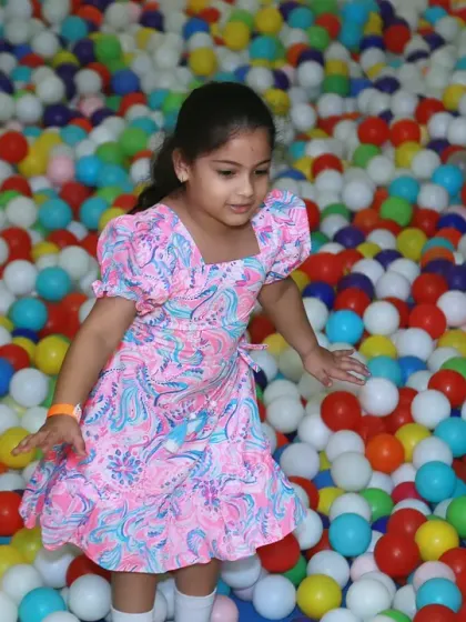 A girl navigating a giant ball pit. The vibrant colors of the balls create a fun and dynamic backdrop for photos of kids at play.