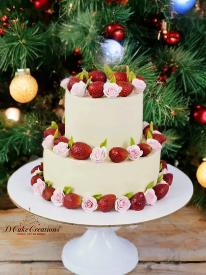 A beautiful two-tier cake decorated with fresh strawberries and delicate pink sugar roses, perfect for a festive or romantic occasion.