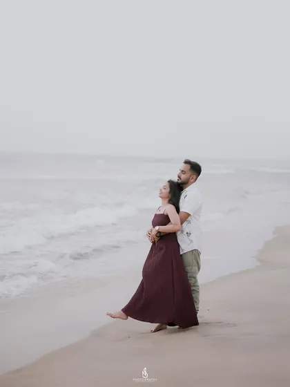 A tender embrace by the water's edge on a misty day. The overcast sky provides soft, even lighting that is perfect for romantic and moody couple photography.