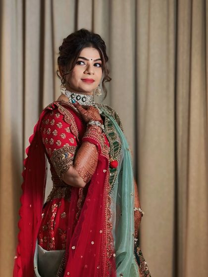 This bride is the picture of elegance in her red and green lehenga. Our team crafted a soft, wavy updo and complementary makeup to match the grandeur of her wedding attire.