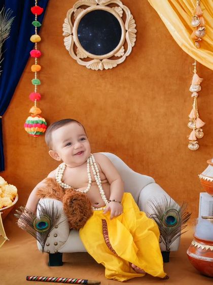 Lounging like a little lord, this baby Krishna is surrounded by peacock feathers and festive decor.
